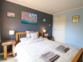 A bedroom with a double bed two bedside tables with lamps and paintings on the wall at 3 Birkbeck Way in Norwich