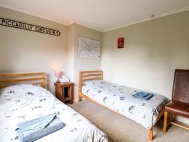 A bedroom with two single beds a wooden nightstand with a lamp and tissue box a chair and wall decorations at 3 Birkbeck Way in Norwich