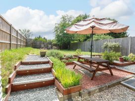 A backyard garden with a picnic table and umbrella gravel steps wooden fences and plants at 3 Birkbeck Way in Norwich