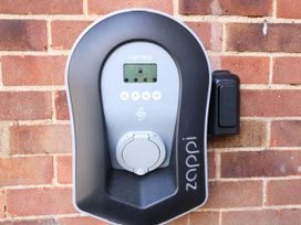 An electric vehicle charging station mounted on a brick wall at 3 Birkbeck Way in Norwich