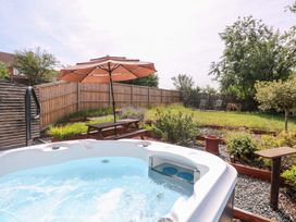 A garden with a hot tub, umbrella, table, and chairs at 3 Birkbeck Way Norwich