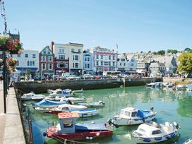 A harbor with small boats docked and buildings along the waterfront at 10 Dartmouth House in Dartmouth