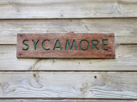 A wooden sign with the word sycamore on a wooden wall at Sycamore Lodge in Rosliston