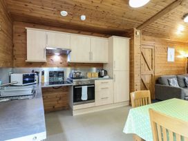 A kitchen with wooden cabinets stainless steel countertops a microwave toaster kettle and a dining table with green polka dot tablecloth at Sycamore Lodge in Rosliston
