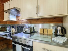A kitchen counter with a toaster kettle canisters microwave and knife block at Sycamore Lodge in Rosliston