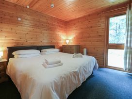 A bedroom with a large bed with white bedding and towels wooden walls and a window at Sycamore Lodge in Rosliston