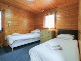 A bedroom with two single beds a wooden chest of drawers and a window at Sycamore Lodge in Rosliston