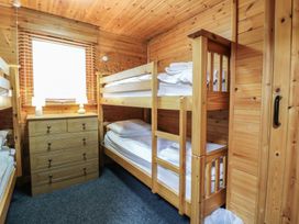 A small wooden bedroom with bunk beds a wooden chest of drawers and a window with blinds at Sycamore Lodge in Rosliston