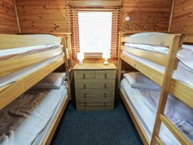A bedroom with two wooden bunk beds and a chest of drawers with two lamps at Sycamore Lodge in Rosliston