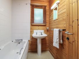 A bathroom with a bathtub sink towel on a rack and a window with blinds at Sycamore Lodge in Rosliston