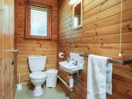 A small bathroom with a toilet sink towel rack and window with blinds at Sycamore Lodge in Rosliston