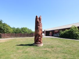 A wooden carved totem with birds and animals on grass outside a visitor centre at Sycamore Lodge in Rosliston