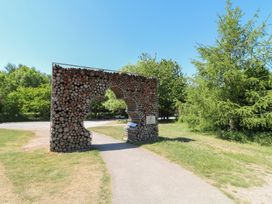 A wooden log art installation with a clover-shaped cutout on a path surrounded by grass and trees