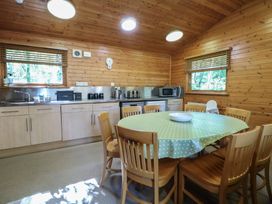 A kitchen with wooden walls a round dining table with chairs and appliances at Cedar Lodge in Rosliston