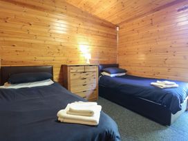 A bedroom with two single beds a wooden chest of drawers and a lamp at Cedar Lodge in Rosliston