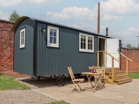 A shepherd's hut with a table and chairs at Shepherd's Hut in Wrexham