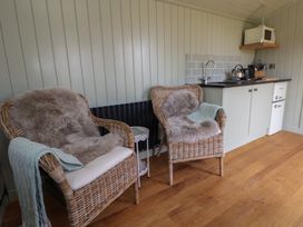 A seating area with chairs and kitchenette at Shepherd's Hut in Wrexham
