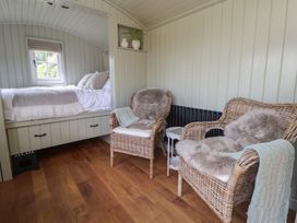 A bedroom with a bed and wicker chairs at Shepherd's Hut in Wrexham