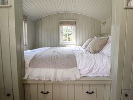 A bedroom with a bed and windows at Shepherd's Hut in Wrexham