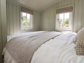 A bedroom with a bed and windows at Shepherd's Hut in Wrexham