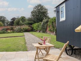 A garden with a hut and seating area at Shepherd's Hut in Wrexham