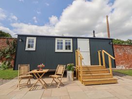 An outdoor area with a hut, table, and chairs at Shepherd's Hut in Wrexham