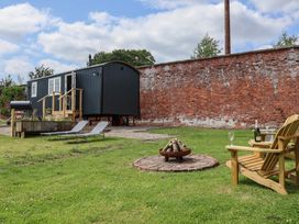 An outdoor space with a hut, fire pit, and chairs at Shepherd's Hut in Wrexham