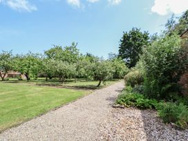 A garden with trees and a gravel path at Shepherd's Hut in Wrexham