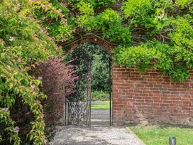 A garden with a brick wall and open gate at Shepherd's Hut in Wrexham