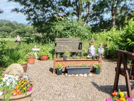 A garden area with a bench surrounded by flower pots at Shepherd's Hut in Wrexham