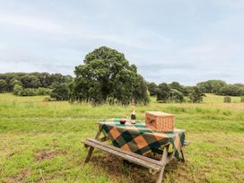 A picnic setup with a table and basket in a field at The Garden Hut in Wrexham