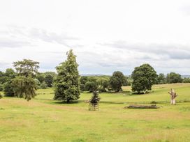 A green field with trees and a fence at The Garden Hut in Wrexham