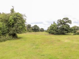 A field with trees and a fence at The Garden Hut in Wrexham