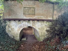 An archway with a brick wall and pathway surrounded by vegetation at The Garden Hut in Wrexham