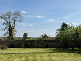 A garden with a tree and brick wall at The Garden Hut in Wrexham