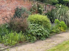 A garden with various plants and a brick wall at The Garden Hut in Wrexham