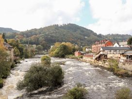 A river with buildings and hills at The Garden Hut in Wrexham