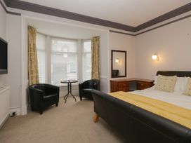 A bedroom with a bed, armchairs, and a television at Norwood House in Ambleside