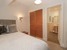 A bedroom with a bed and nightstand leading to a bathroom at Norwood House in Ambleside