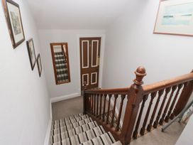 A stairway with wooden railing and photographs at Norwood House in Ambleside