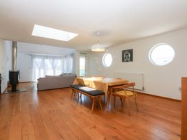 A living room with a dining area and windows at Shearwater Rhosneigr