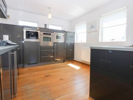 A kitchen with built-in appliances and wooden flooring at Shearwater in Rhosneigr