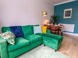 A living room with a green sofa and dining table at Seagull & Chips in Weymouth