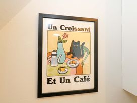 A framed artwork featuring a cat, coffee, and croissant in the dining room at Seagull & Chips in Weymouth