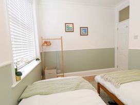 A bedroom with twin beds and a clothes rack at Seagull & Chips in Weymouth