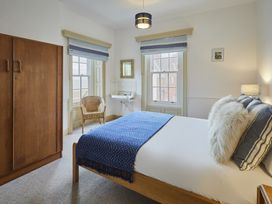 A bedroom with a bed, wardrobe, and window at Beachside Cottage in Sandsend