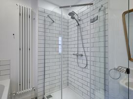 A shower enclosure with glass doors and tiles at Beachside Cottage in Sandsend