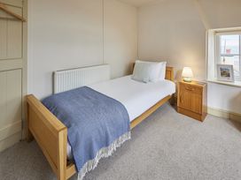 A bedroom with a single bed, nightstand and lamp at Beachside Cottage in Sandsend