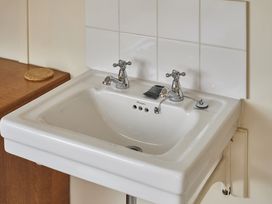 A sink with faucets and wall tiles at Beachside Cottage in Sandsend