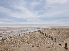 A view of a beach with pebbles and wooden posts at Beachside Cottage in Sandsend